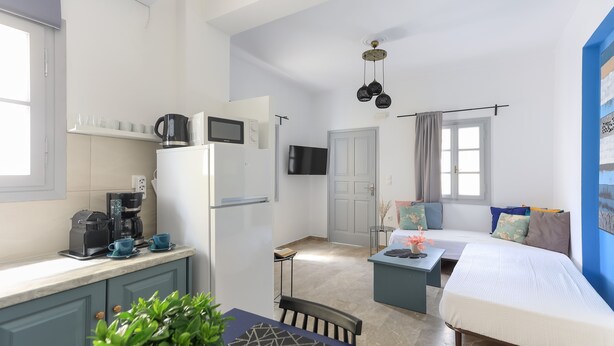A compact living space with a kitchenette, a bed, a dining area, and a small seating area. - Azul Home - Ahilli Slow Living (Καμάρι)