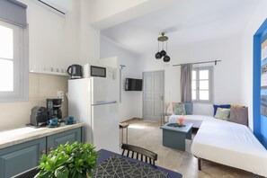 Een compacte leefruimte met een kitchenette, een bed, een eethoek en een kleine zithoek.