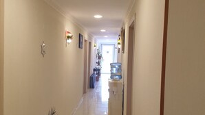 Un pasillo de hotel con dispensador de agua, plantas en macetas y una puerta al final.