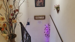 Una escalera con un jarrón de flores a la izquierda, un cuadro en la pared y un letrero solicitando pago inmediato.