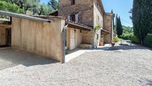 A stone building with a sloped roof, a gravel courtyard, and a tennis court. - Beautiful home in Fayence (Fayence)