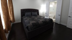 A bedroom with a dark wood floor, a tufted headboard bed, and a patterned bedspread. - "modern 3bed Townhome. Near Nrg" (Houston)