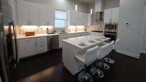 A modern kitchen with white cabinets, a central island with bar stools, a built-in microwave, and a stainless steel refrigerator. - "modern 3bed Townhome. Near Nrg" (Houston)