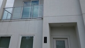A multi-story building with a white facade, multiple windows, and a balcony with glass railings. - "modern 3bed Townhome. Near Nrg" (Houston)