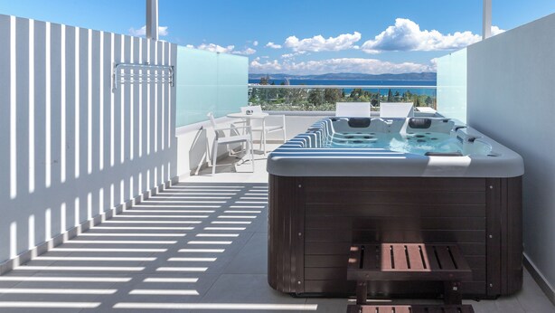Une terrasse sur le toit avec un jacuzzi, des sièges extérieurs et une vue sur la mer.