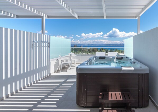 A rooftop terrace with a hot tub, outdoor seating, and a view of the sea.