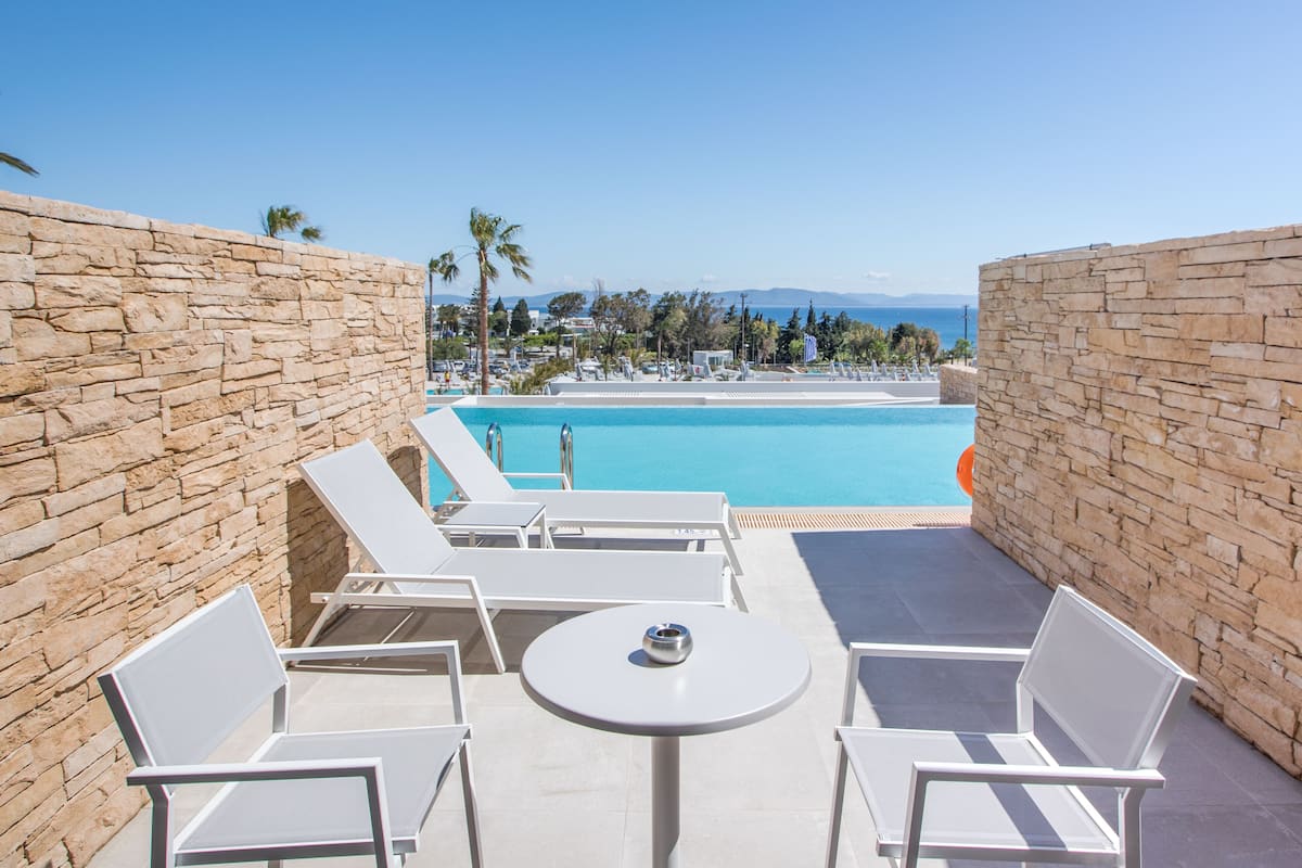 A poolside area with stone walls, white lounge chairs, and a table.