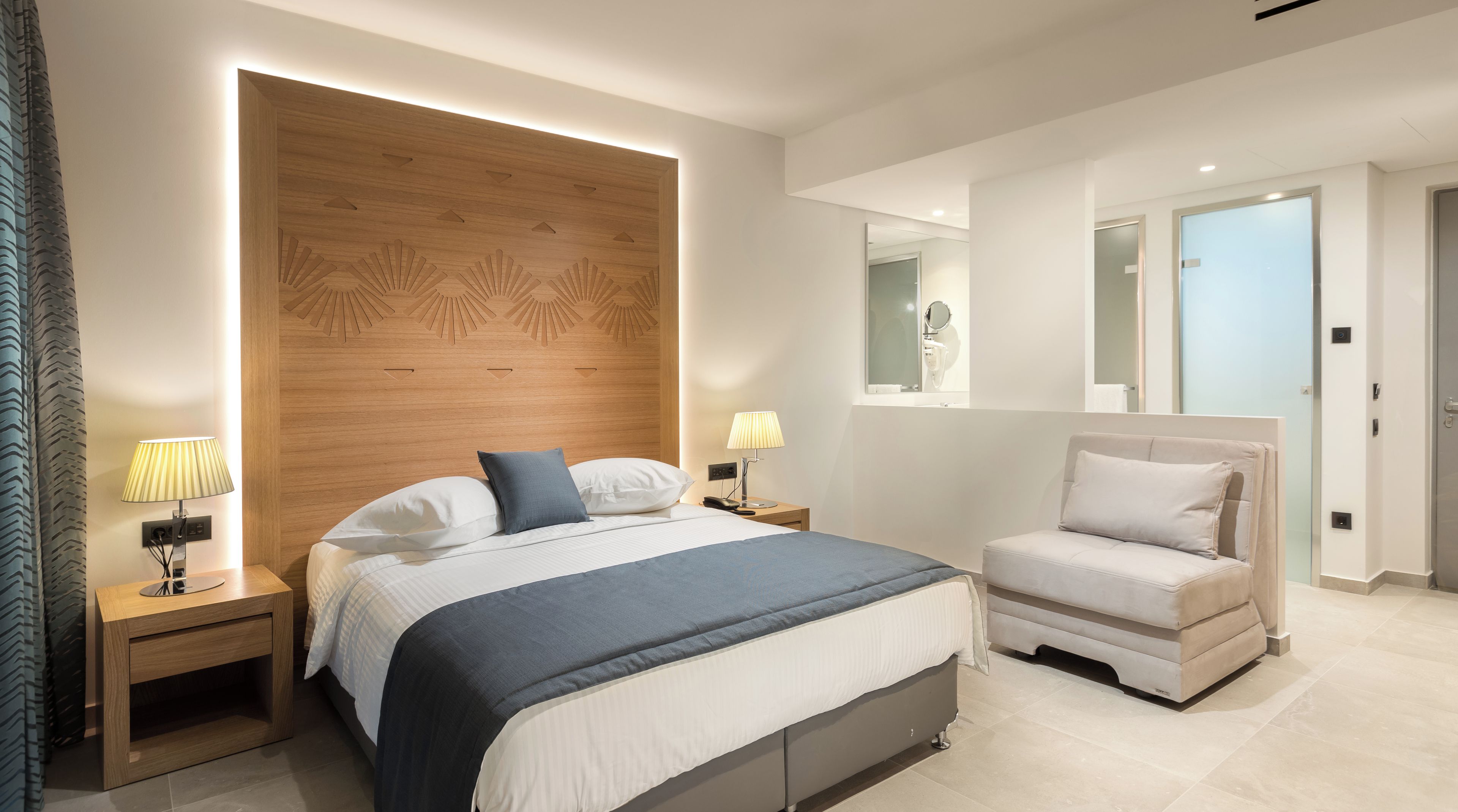 A modern bedroom with a large bed, bedside tables, a chair, and a mirror.
