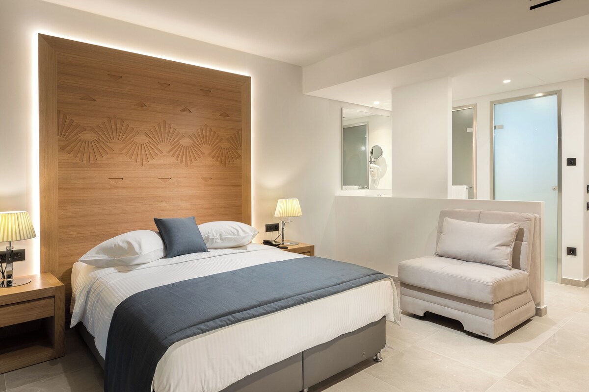A modern bedroom with a large bed, bedside tables, a chair, and a mirror.