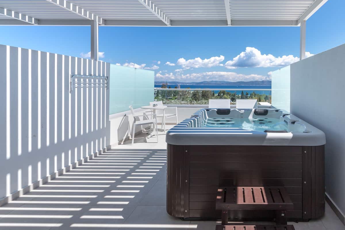 A rooftop terrace with a hot tub, outdoor seating, and a view of the sea.