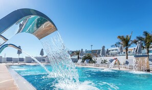 A pool with a water feature, clear blue sky, and lounge chairs in the background. - Blue Lagoon Ocean (Kos)