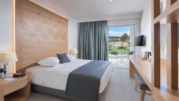 Ein modernes Hotelzimmer mit Bett, Nachttisch, Lampe und Blick ins Freie.