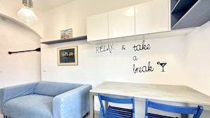 Een moderne woonkamer met een blauwe bank, een eettafel met blauwe stoelen, en een muur met een motiverende quote.