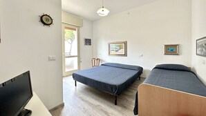 Een kamer met twee bedden, een televisie en een deur naar buiten.