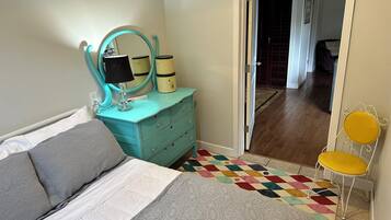 A bedroom with a bed, a dresser with a mirror, a lamp, and a chair.