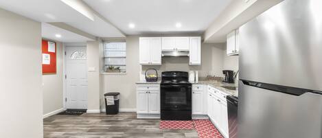 A modern kitchen with white cabinets, a stainless steel refrigerator, and a black oven.