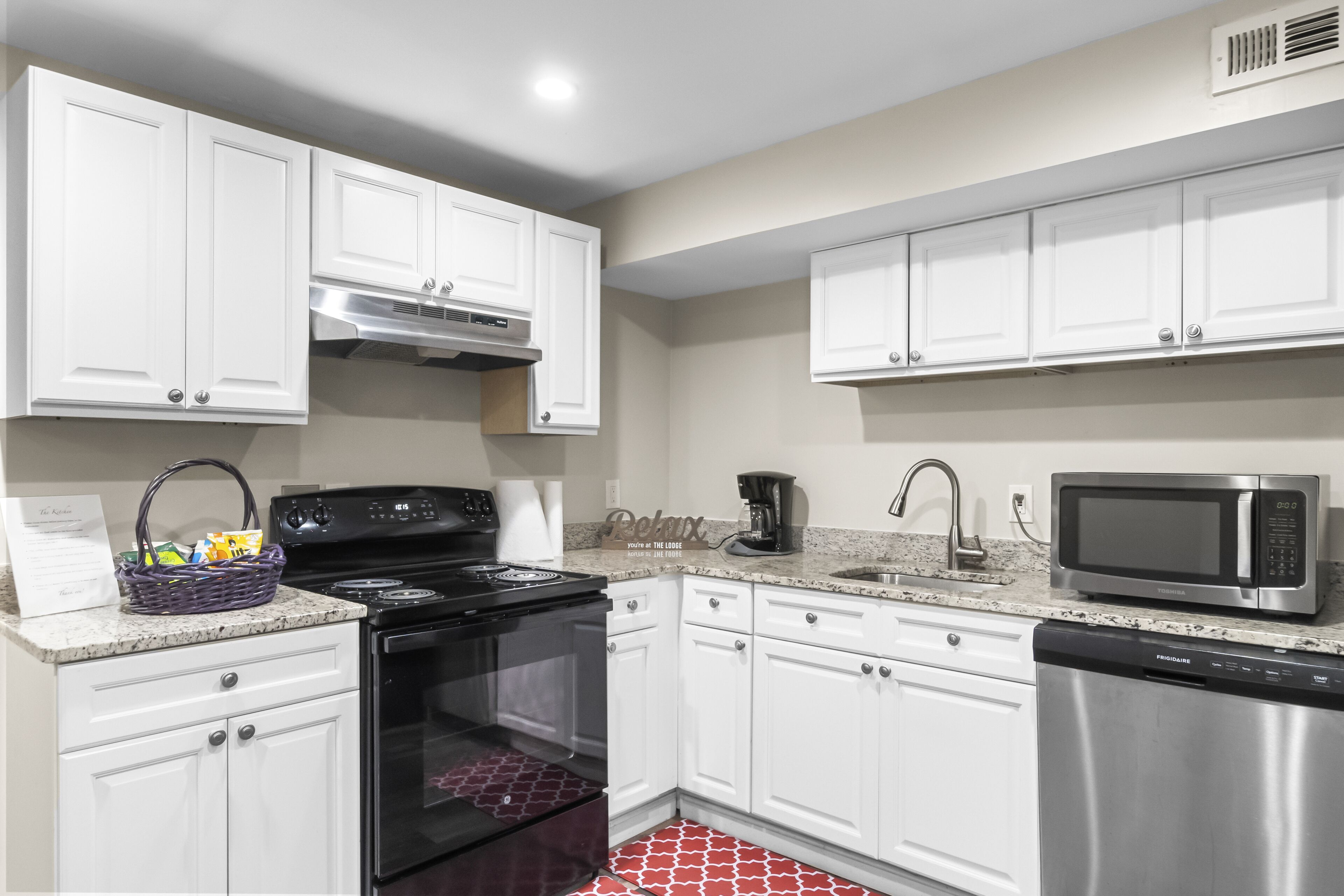 A modern kitchen with white cabinets, a stainless steel stove, a microwave, and a dishwasher.