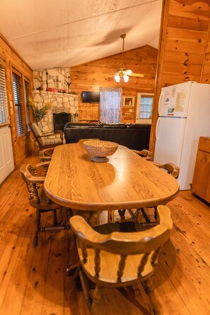 Cozy room with a large dining table, stone fireplace, and flat-screen TV.