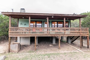 Situated in a natural setting, this charming structure features a simple design with a flat roof and a balcony supported by wooden beams.