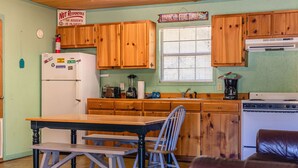 Une cuisine avec des meubles de rangement en bois, un réfrigérateur, une cuisinière et une table à manger avec des chaises.
