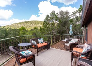 A deck with wicker furniture and a view of a forested hillside. - Family Tradition vacation home located in the Canyon Oaks Subdivision (Concan)