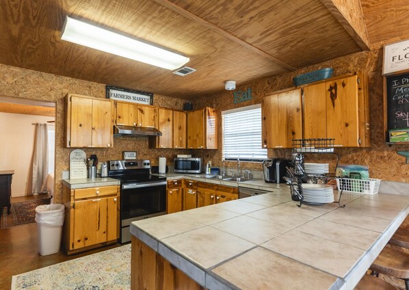 A kitchen with wooden cabinets, a large island, and a chalkboard menu. - Family Tradition vacation home located in the Canyon Oaks Subdivision (Concan)