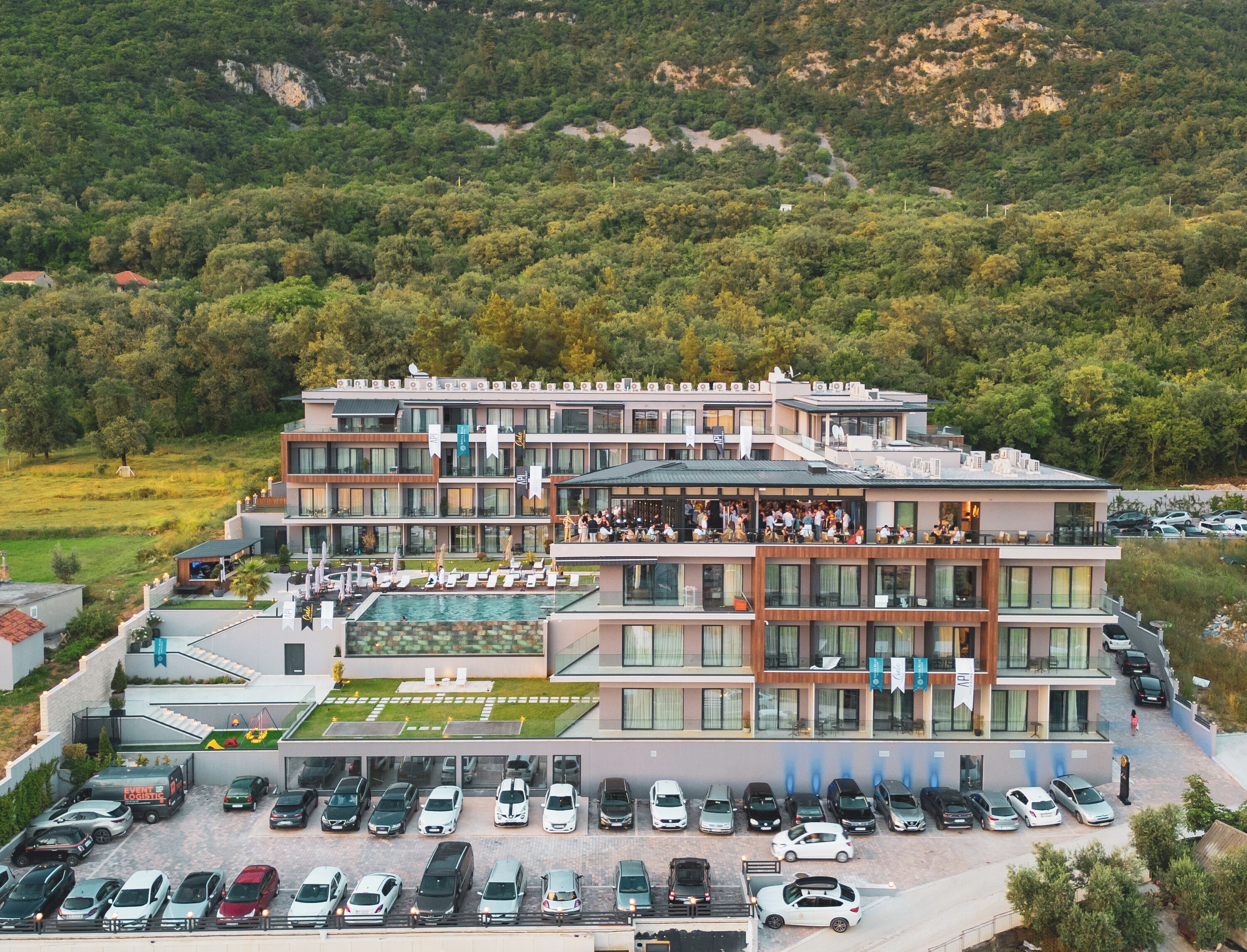 A modern hotel with multiple floors, a rooftop pool, and a parking lot.