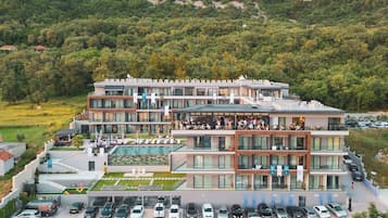 A modern hotel with multiple floors, a rooftop pool, and a parking lot.