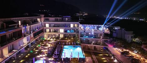 A multi-story hotel with a rooftop pool, outdoor seating, and a bar area.
