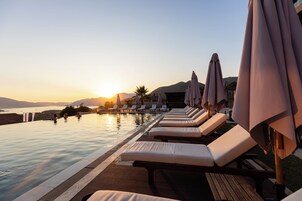 Una piscina al aire libre, sombrillas, sillones reclinables de piscina