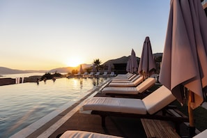 A poolside area with lounge chairs and umbrellas, overlooking a body of water and mountains during sunset. - Royal Blue Resort & Residence (Kotor)