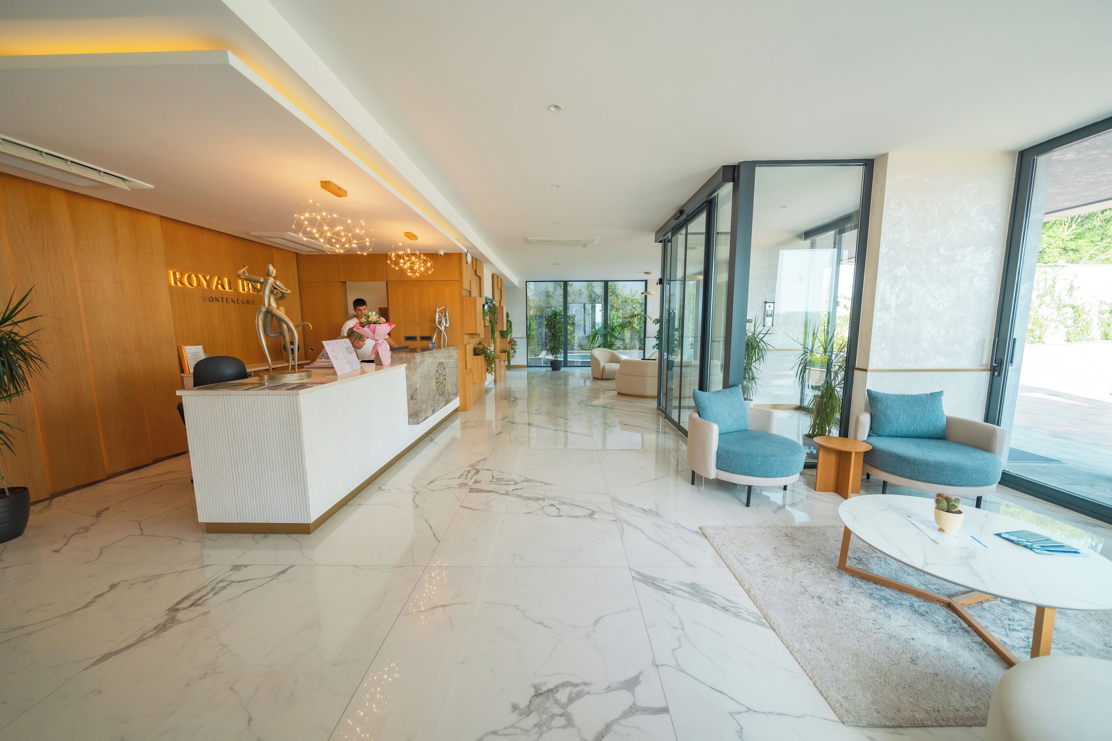 Un vestíbulo moderno de hotel con mostrador de recepción, zona de estar y ventanas amplias.