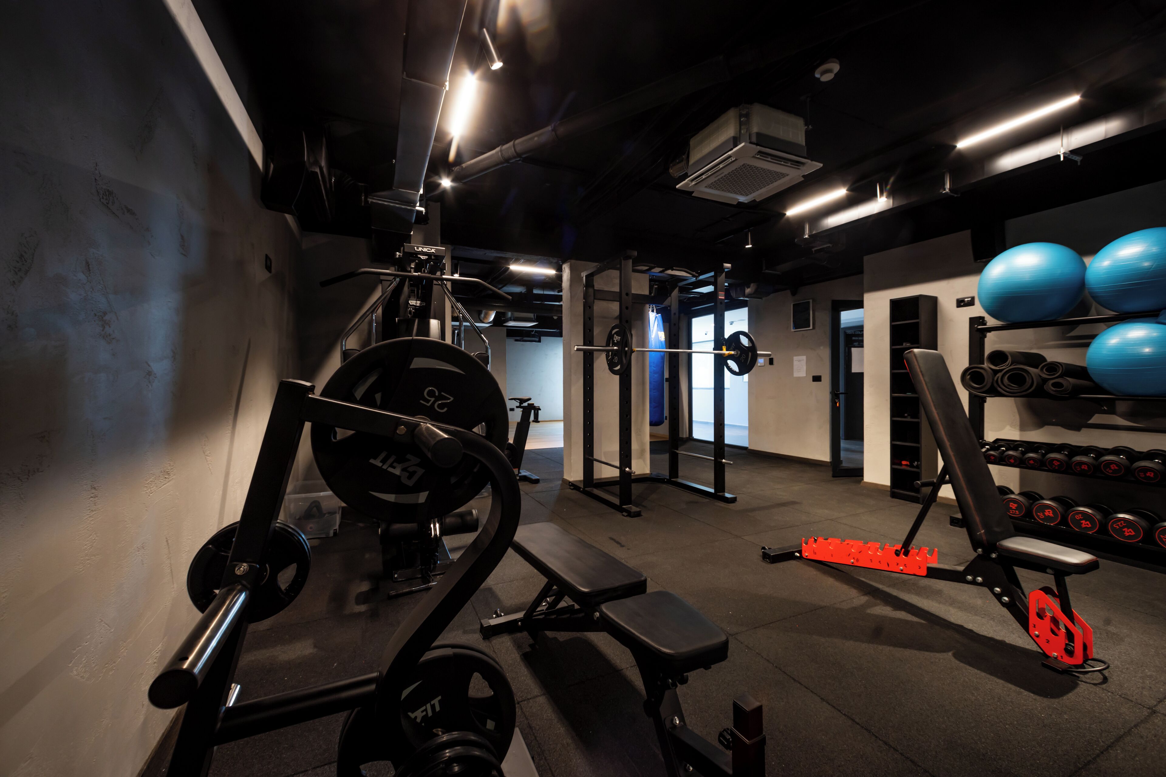 A gym with weightlifting equipment, a bench, and exercise balls.