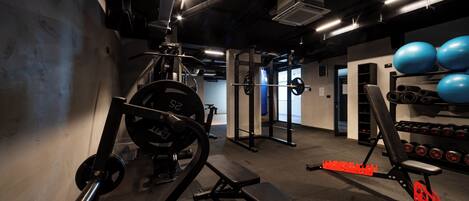 Un gimnasio con equipo de levantamiento de pesas, una banca y pelotas de ejercicio.