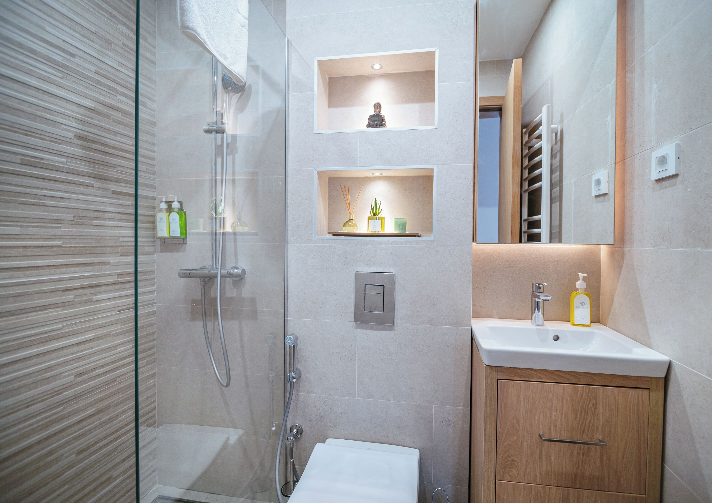 Ein modernes Badezimmer mit einer gläsernen Duschkabine, einem weißen Waschbecken und Holzschränken.