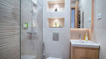 Ein modernes Badezimmer mit einer gläsernen Duschkabine, einem weißen Waschbecken und Holzschränken.