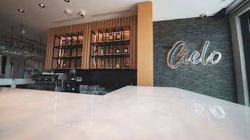 Uma área de bar moderna com estantes de madeira e um letreiro de neon com a palavra "Cielo".