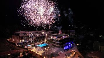 A hotel with a swimming pool, outdoor lighting, and a parking lot.