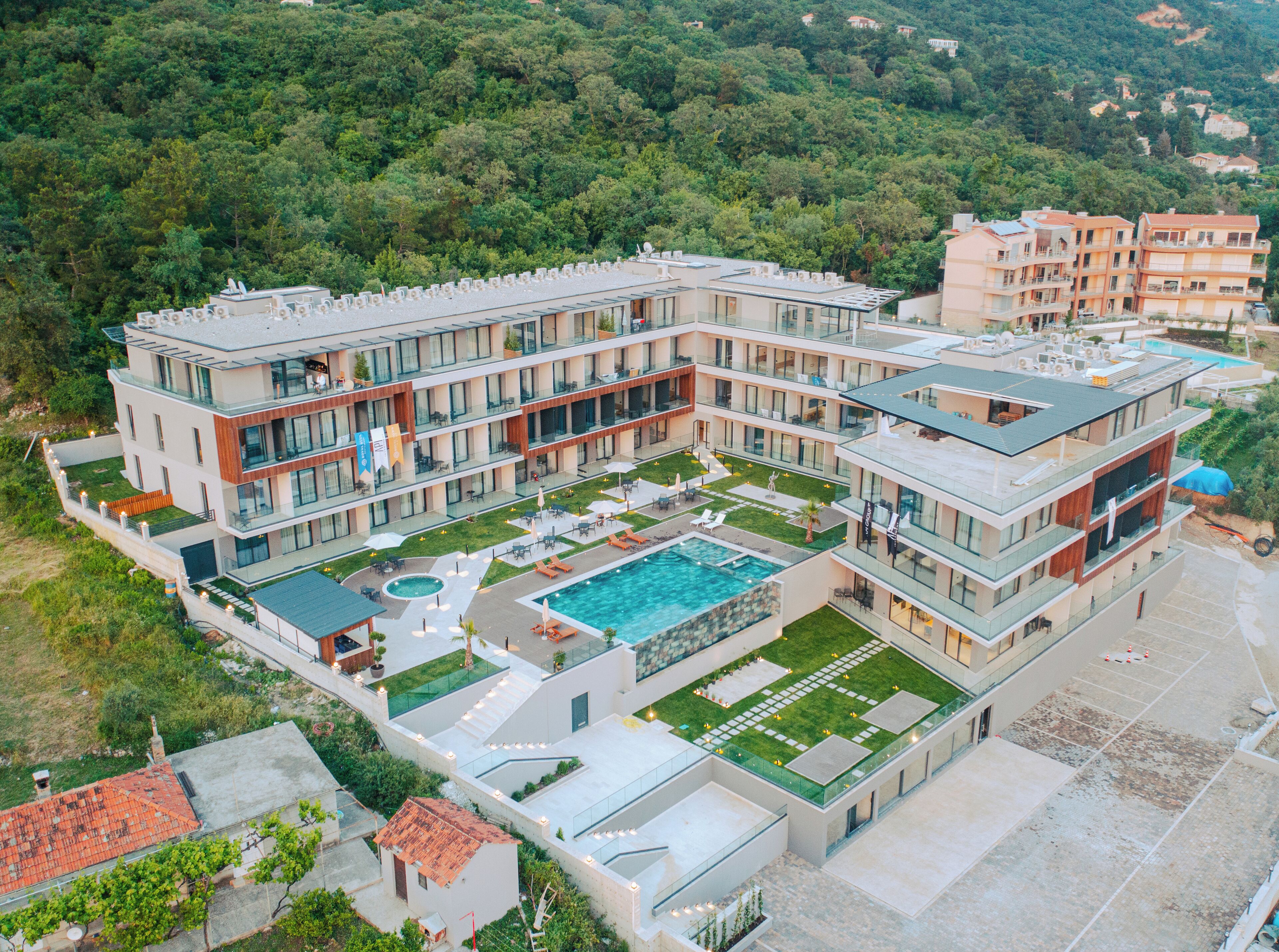 A multi-story hotel with a rooftop pool, outdoor seating areas, and a landscaped courtyard.