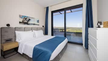 Una habitación de hotel moderna con una cama grande, una mesita de noche, un tocador y un balcón con vistas al paisaje.
