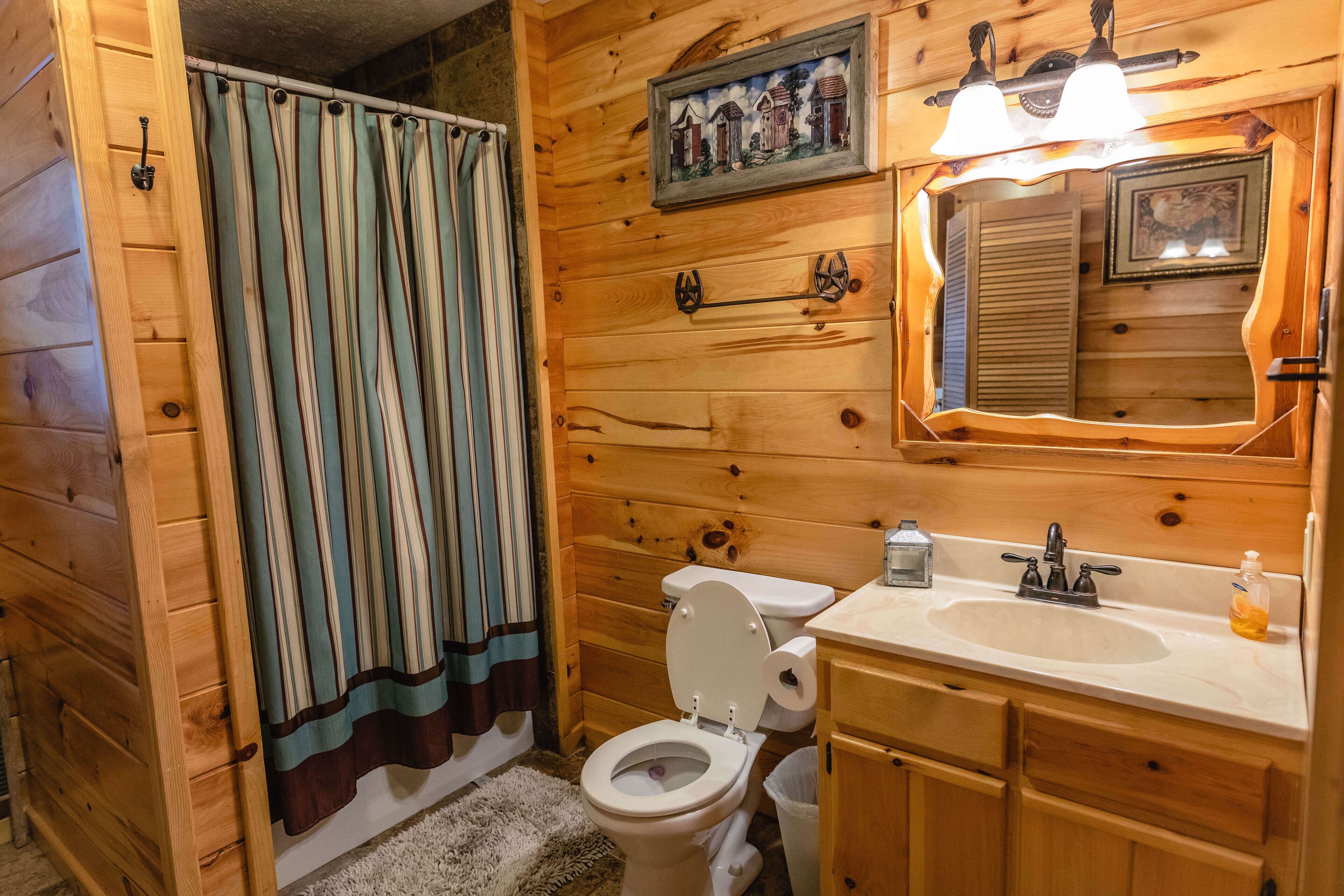 A wooden cabin bathroom with a toilet, sink, and mirror.