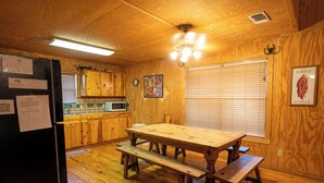 A wooden kitchen with a wooden table and benches, a refrigerator, wooden cabinets, a microwave, and a clock on the wall. - Spacious home with a great view! (Concan)