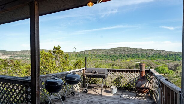 A wooden deck with a barbecue grill, a portable grill, and a pottery piece. - Spacious home with a great view! (Concan)