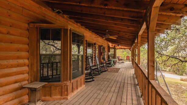 A wooden log cabin with a covered porch, large windows, and outdoor seating. - Great Vacation Home with wrap around porch (Concan)