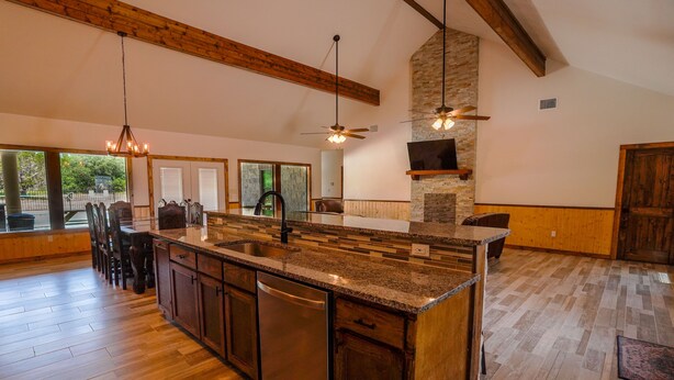 A spacious kitchen with a large island, wooden flooring, and a stone accent wall. - New custom home located in the Mountain Valley subdivision (Concan)