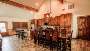 A spacious kitchen with wooden cabinets, a central island with bar stools, and a dining table with chairs. - New custom home located in the Mountain Valley subdivision (Concan)