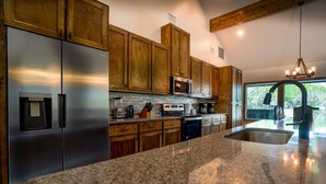 A kitchen with stainless steel appliances, wooden cabinets, a granite countertop, and a view of the outdoors. - New custom home located in the Mountain Valley subdivision (Concan)