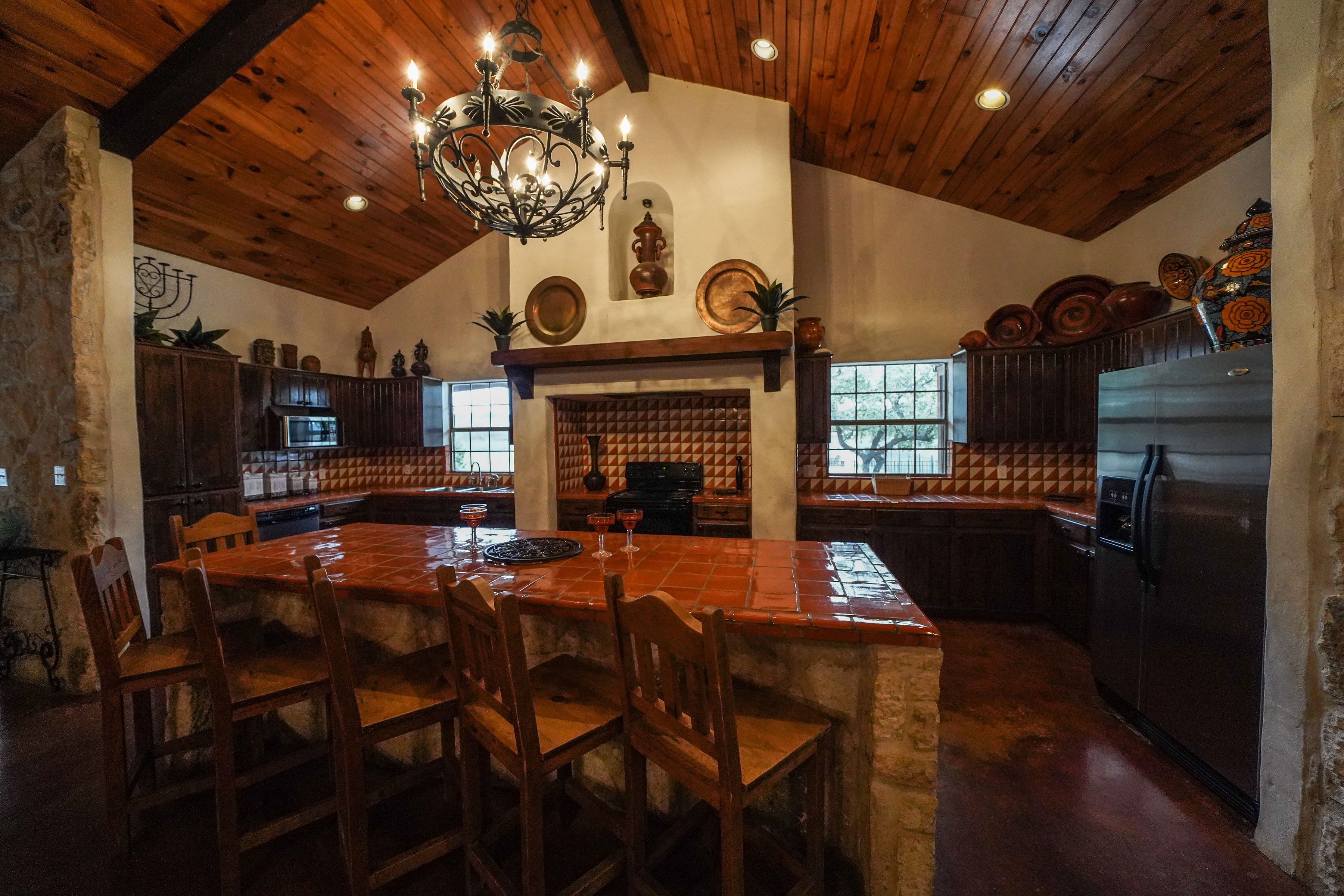 A spacious kitchen with a large island, wooden ceiling, and a stone wall.