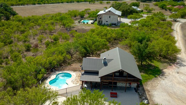 A large house with a swimming pool, surrounded by trees and open fields. - Spacious home located in Mountain Valley (Concan)