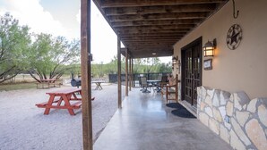 An outdoor patio area with picnic tables, a barbecue grill, and a covered seating area. - Spacious home located in Mountain Valley (Concan)
